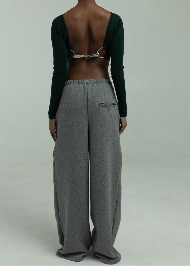 Person wearing a green top and gray sweatpants on a plain background